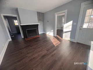 a view of a livingroom with wooden floor and a fireplace
