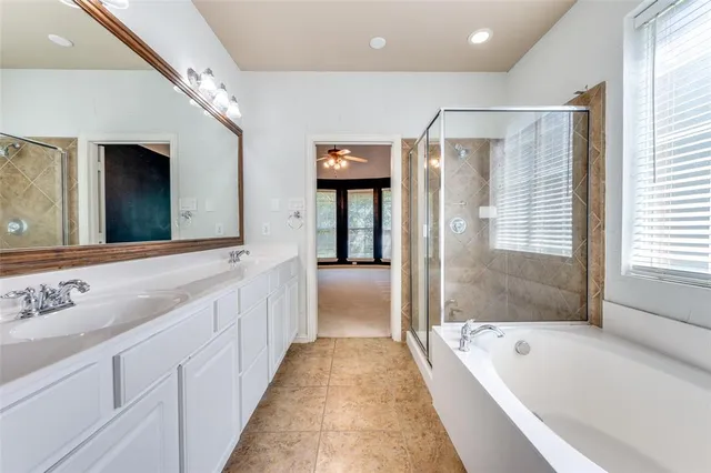 a bathroom with a tub a double vanity sink and mirrors