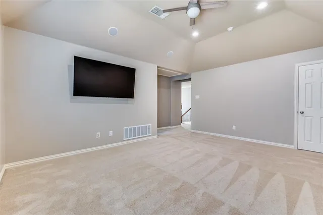 a view of an empty room with a flat screen tv and a ceiling fan