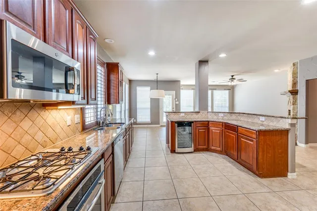 a kitchen with stainless steel appliances granite countertop a stove a sink and a microwave