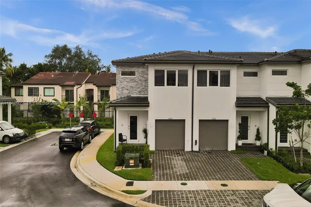 a view of a white house with a yard and potted plants