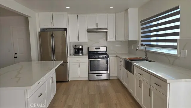 an empty room with wooden floor and kitchen view