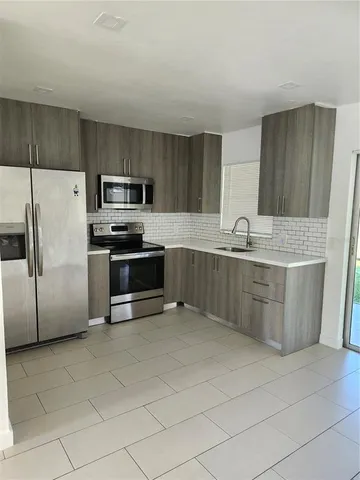 a kitchen with stainless steel appliances a sink a stove a microwave a sink a refrigerator and cabinets