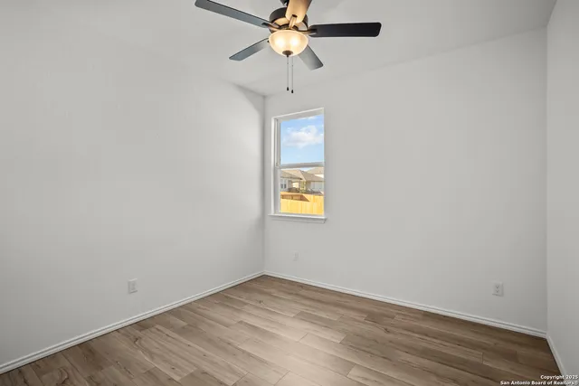 an empty room with a window and a ceiling fan