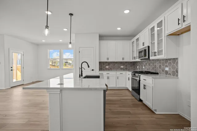 a kitchen with stainless steel appliances granite countertop a sink stove and white cabinets with wooden floor