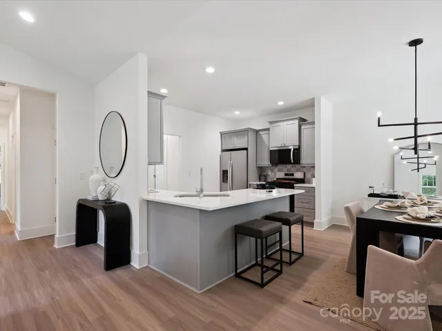 a kitchen with stainless steel appliances granite countertop a table chairs in it and wooden floors