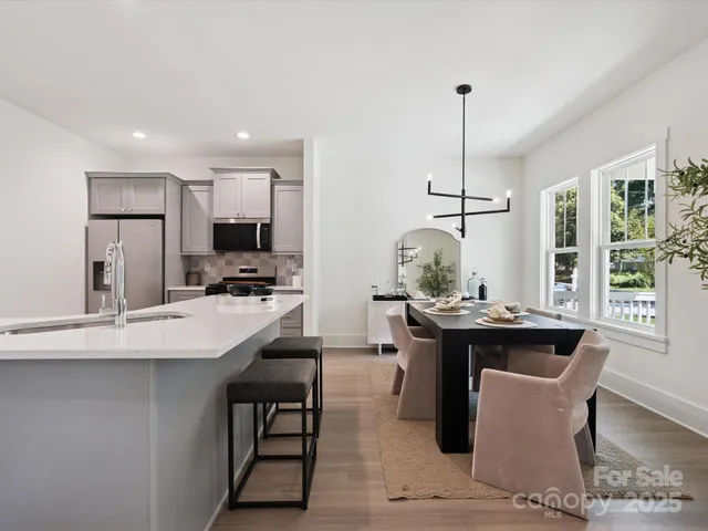a kitchen with kitchen island a dining table chairs and white cabinets