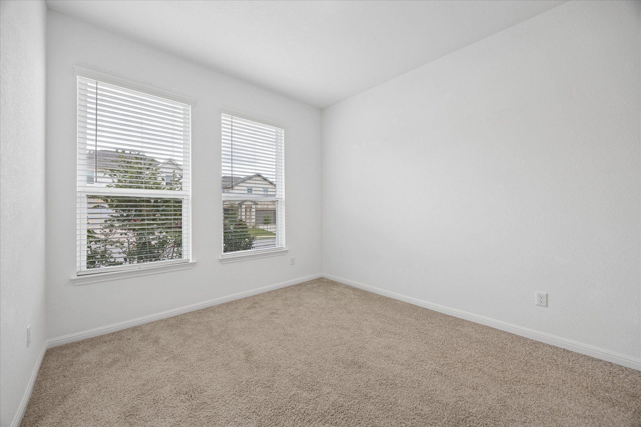 6407 Rounded Pebble Lane Buda, TX 78610 - Photo 19 of 32 A spacious, naturally illuminated room featuring warm carpet flooring and two generous windows.