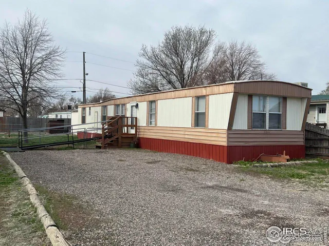 a view of a house with a small yard and large tree