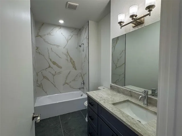 a bathroom with a granite countertop sink a toilet and bathtub