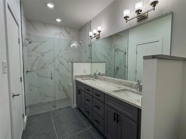 a bathroom with a granite countertop sink a large mirror and a shower