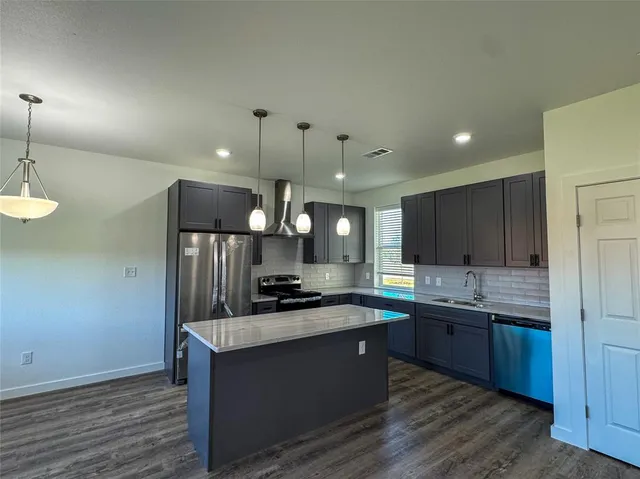 a kitchen with stainless steel appliances granite countertop a sink a stove and a refrigerator