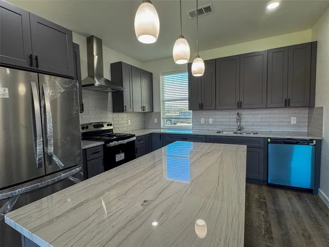a kitchen with stainless steel appliances granite countertop a sink stove and refrigerator