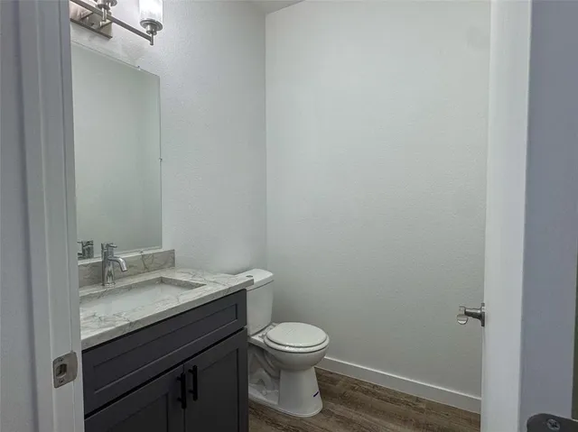 a bathroom with a granite countertop toilet a sink and a mirror