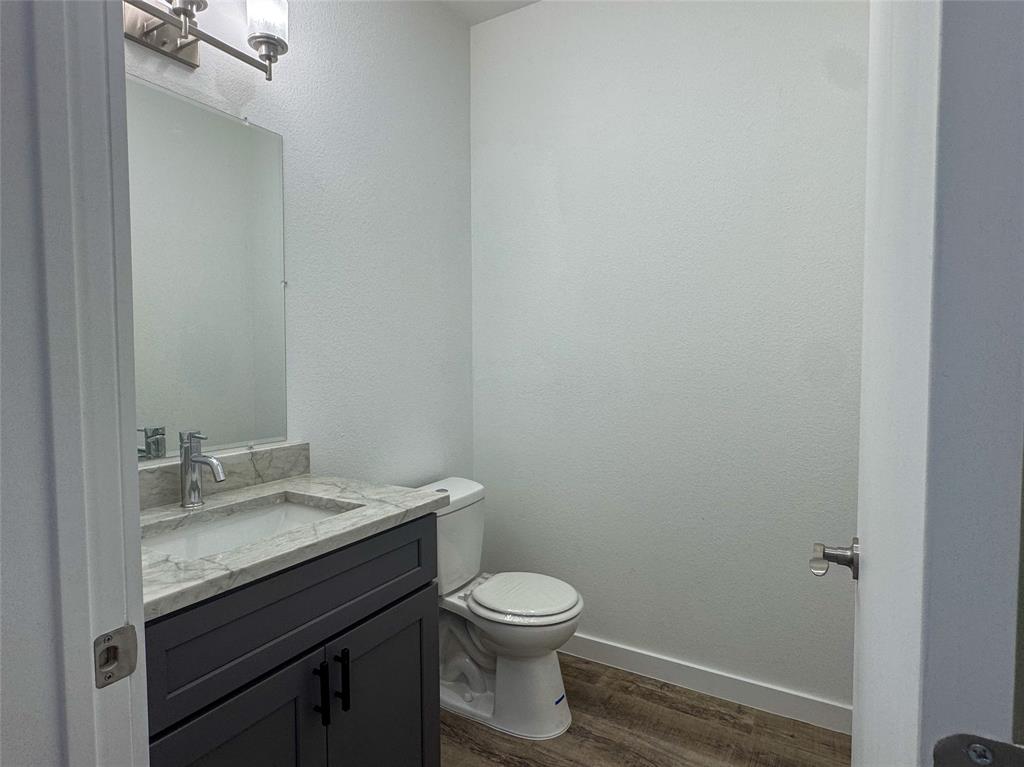 430 Lucy Road Greenville, TX 75402 - Photo 10 of 17 a bathroom with a granite countertop toilet a sink and a mirror