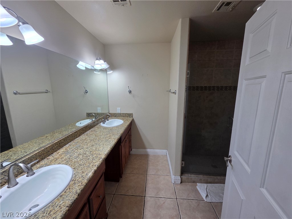 3381 Westwind Road Las Vegas, NV 89146 - Photo 13 of 52 Double vanity with stone countertops and a tiled walk-in shower provide a functional and sleek space.