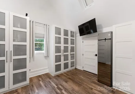 a view of an empty room with wooden floor and cabinet