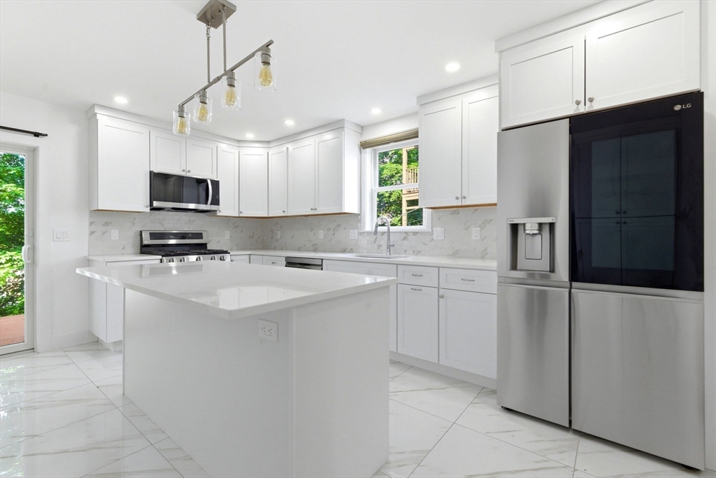 123 Nottinghill Road, Unit 2 Boston, MA 02135 - Photo 4 of 30 a kitchen with kitchen island white cabinets and refrigerator