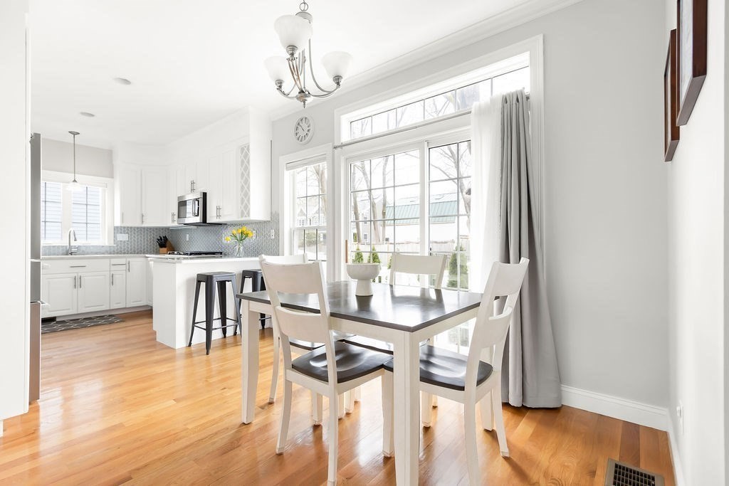 7 Maple Place Needham, MA 02492 - Photo 7 of 26 a kitchen with stainless steel appliances granite countertop a stove top oven a sink a dining table and chairs with wooden floor