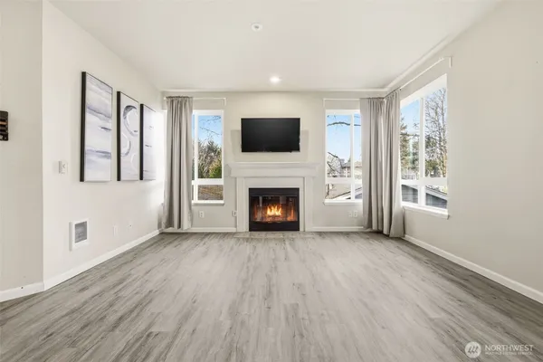 a view of an empty room with wooden floor fireplace and a window