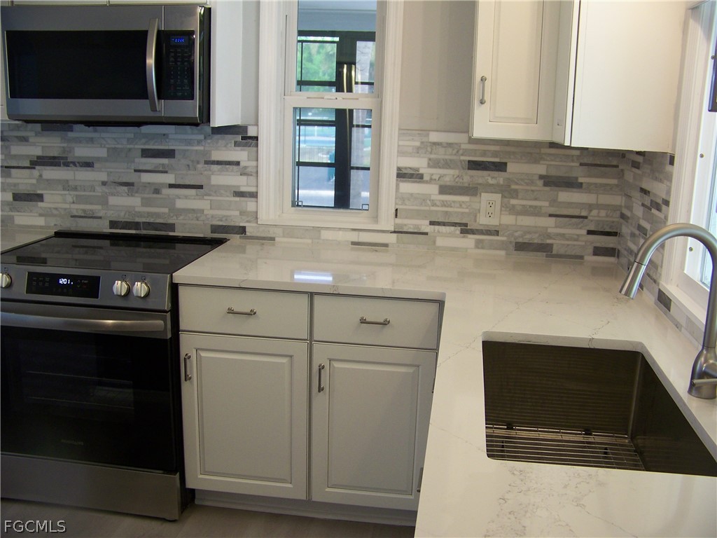 15550 Burnt Store Road, Unit 202 Punta Gorda, FL 33955 - Photo 13 of 50 a kitchen with stainless steel appliances a stove microwave and sink