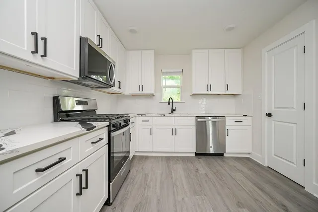 a kitchen with cabinets stainless steel appliances and wooden floor