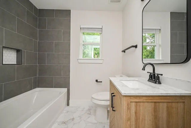 a bathroom with a granite countertop sink a toilet and bathtub