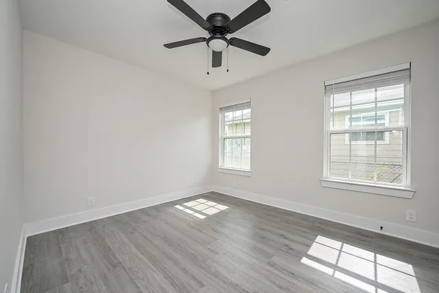 a view of an empty room with wooden floor and a window