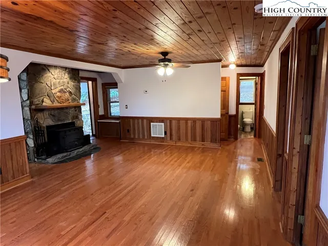 a view of an empty room with wooden floor and a fireplace