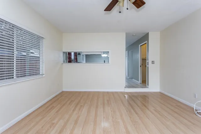 a view of an empty room with wooden floor and a window