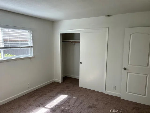a view of an empty room with closet and a window