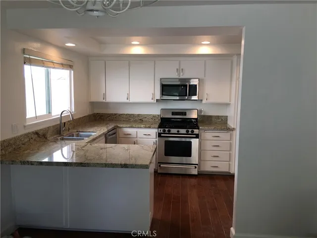 a kitchen with granite countertop a sink and steel appliances