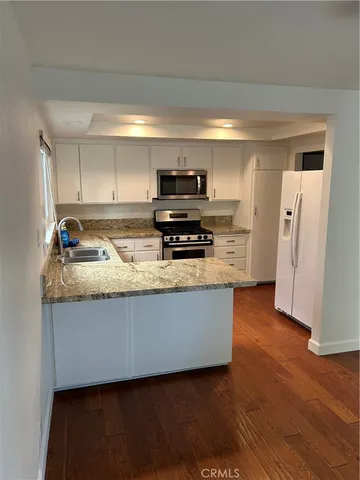 a kitchen with granite countertop a refrigerator and a stove top oven