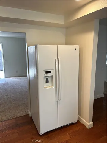 a white refrigerator freezer and a wooden floor