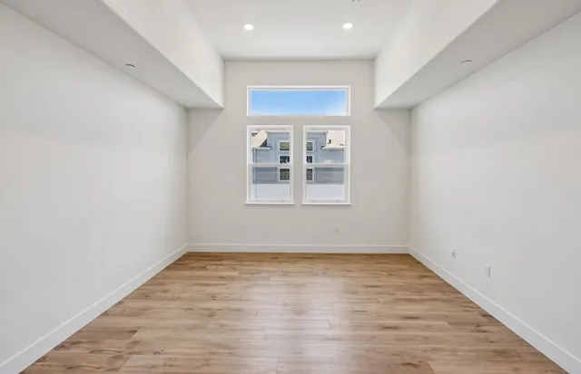 an empty room with wooden floor and windows