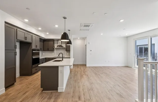 a open kitchen with stainless steel appliances granite countertop a refrigerator a oven a sink and white cabinets with wooden floor