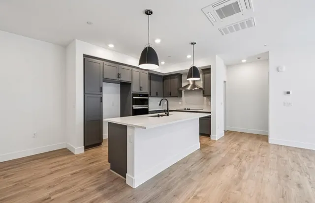 a view of a kitchen with kitchen island stainless steel appliances wooden floor and living room view
