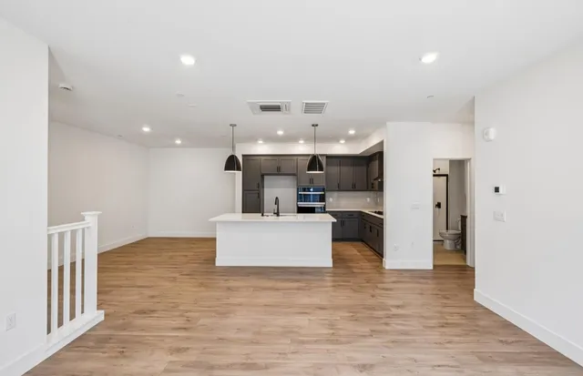 a large kitchen with a refrigerator and a wooden floor