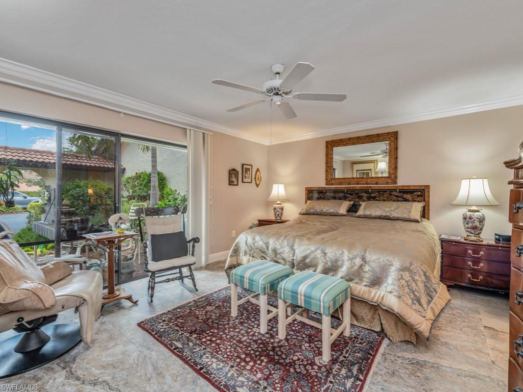 594 Augusta Boulevard, Unit 3 Naples, FL 34113 - Photo 13 of 20 a bedroom with a bed a table and chair with a large mirror next to a window