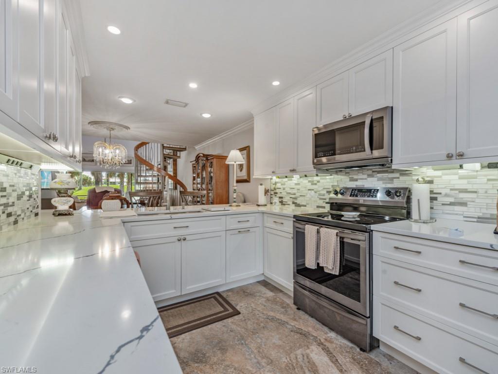 594 Augusta Boulevard, Unit 3 Naples, FL 34113 - Photo 7 of 20 a kitchen with stainless steel appliances granite countertop a stove a sink and a microwave