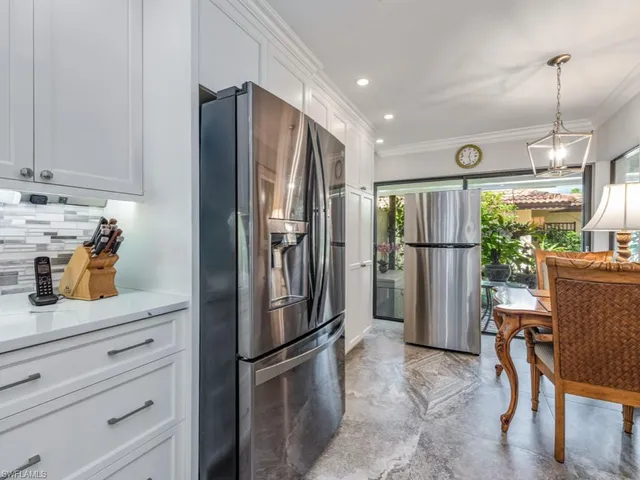 a kitchen with refrigerator a microwave a dining table and chairs