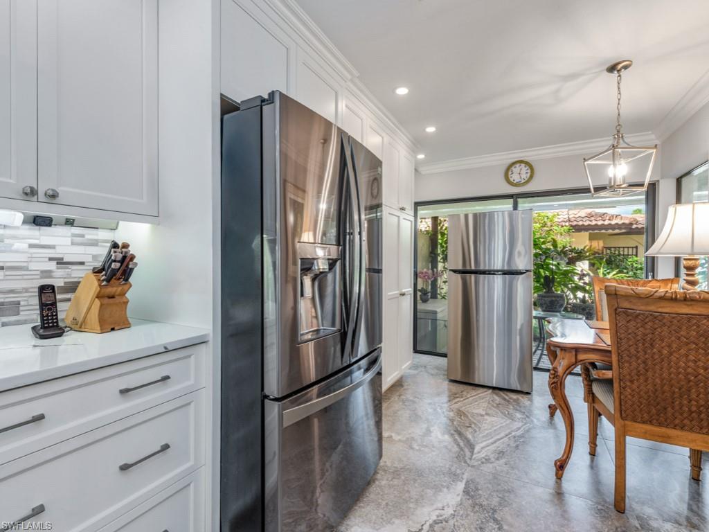 594 Augusta Boulevard, Unit 3 Naples, FL 34113 - Photo 8 of 20 a kitchen with refrigerator a microwave a dining table and chairs