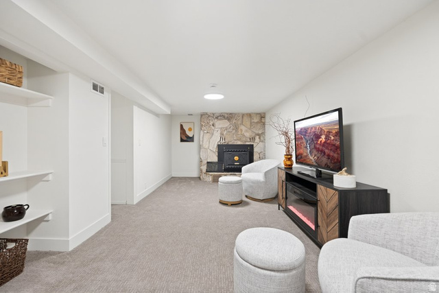 673 East 700 South Springville, UT 84663 - Photo 27 of 43 Spacious room featuring a stone-clad fireplace with a black insert, light gray carpeting, crisp white walls, and built-in shelving