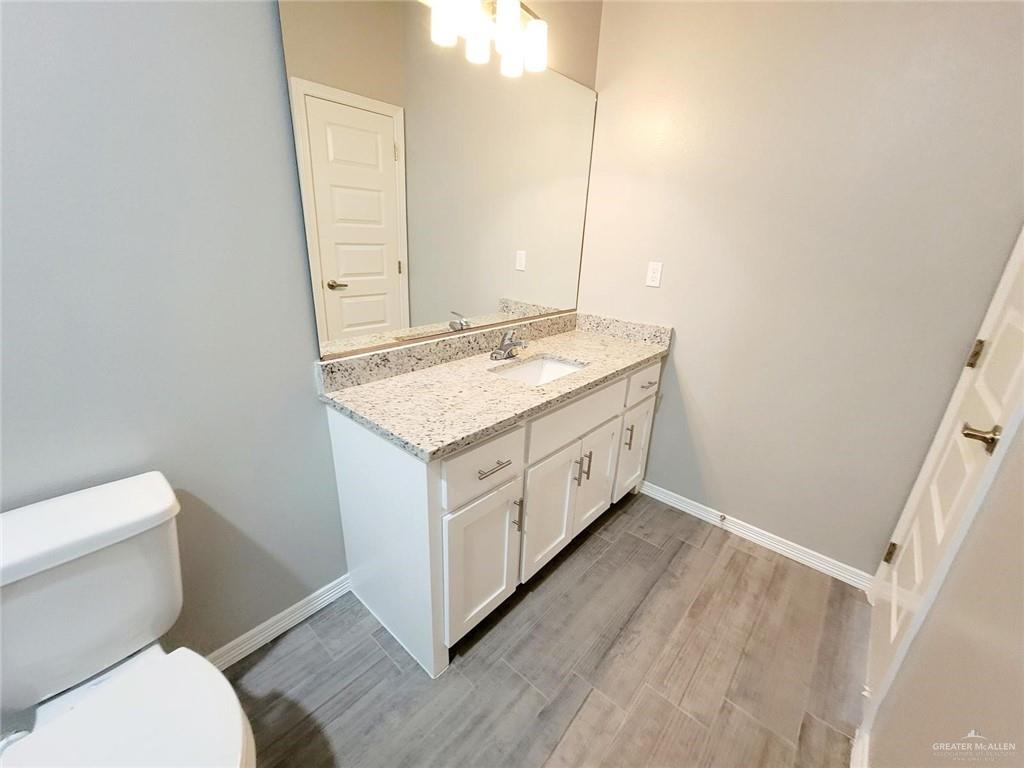 2109 Stauffer Street, Unit 4 Weslaco, TX 78596 - Photo 8 of 14 a bathroom with a granite countertop toilet sink and mirror