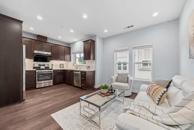 a living room with furniture kitchen and a wooden floor