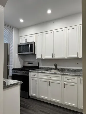 a kitchen with granite countertop white cabinets and stainless steel appliances