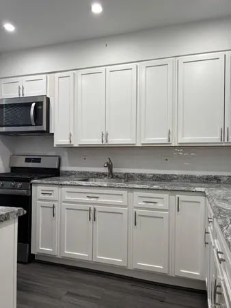 a kitchen with stainless steel appliances granite countertop a stove a sink and white cabinets