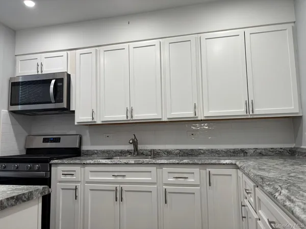 a kitchen with granite countertop white cabinets and stainless steel appliances