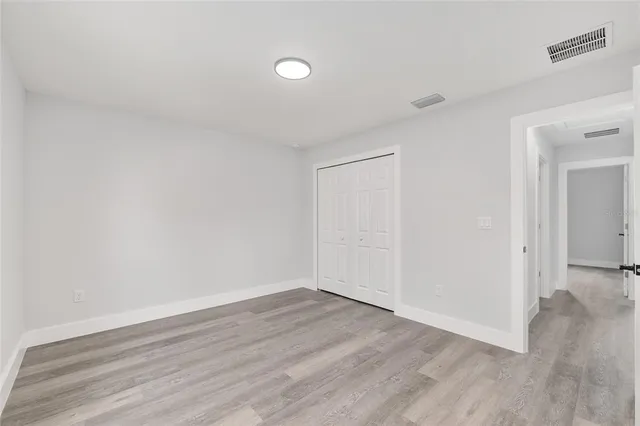 a view of an empty room with wooden floor and closet