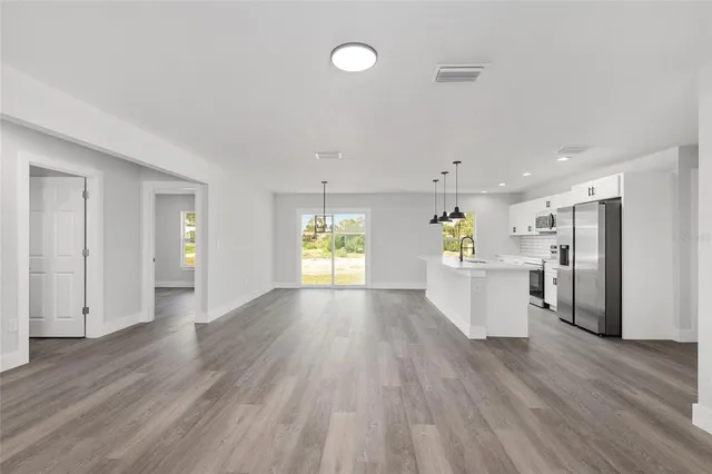 a view of a kitchen with wooden floor and a refrigerator